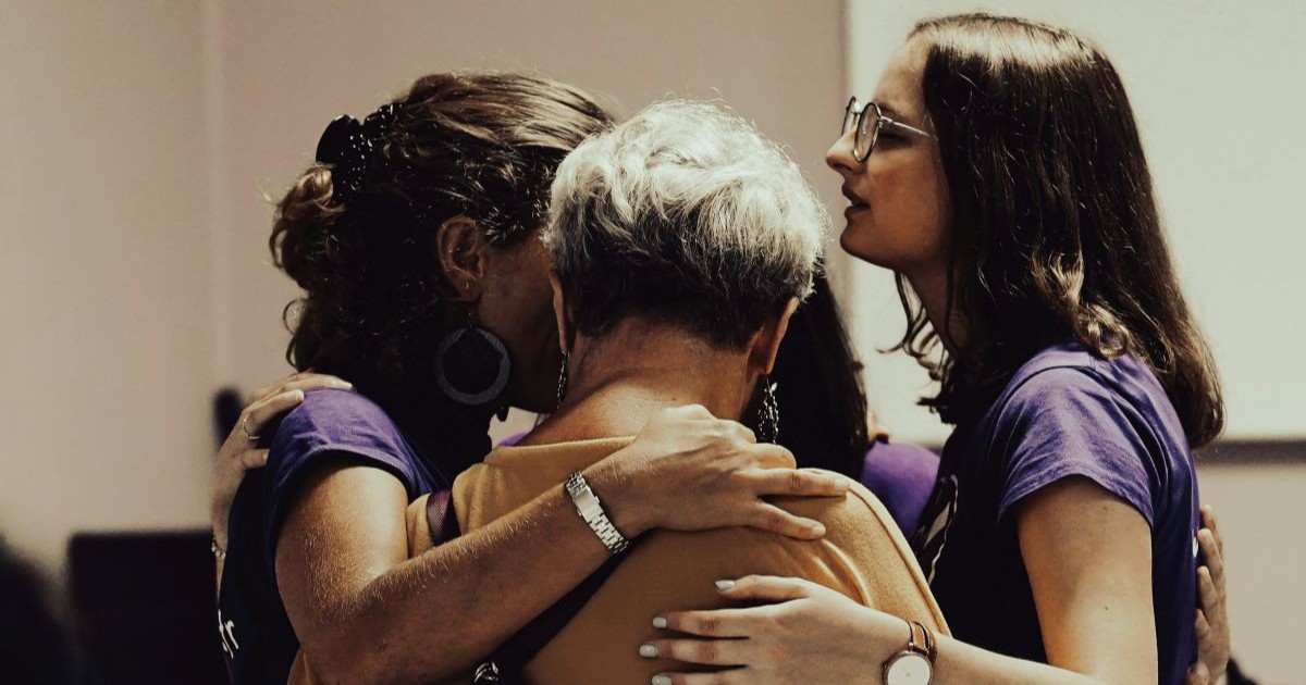 4 women standing in a circle with their arms around each other in support
