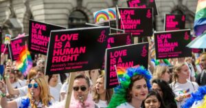 Lots of people marching in a protest to stand up for LGBTQ+ people's rights
