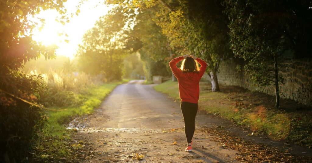 Woman walking down a farm lane road with the fun out.